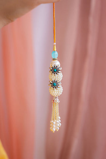 Elegant Pearl Latkan Rakhi with Silver Floral Accents and Tassels – Aneytri