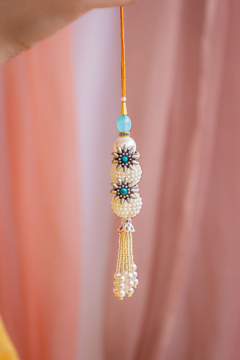 Elegant Pearl Latkan Rakhi with Silver Floral Accents and Tassels – Aneytri